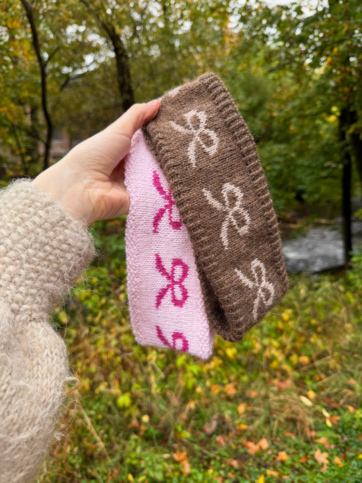 to pannebånd som blir holdt opp med skog i bakgrunnen, et i rosa og et i brunt